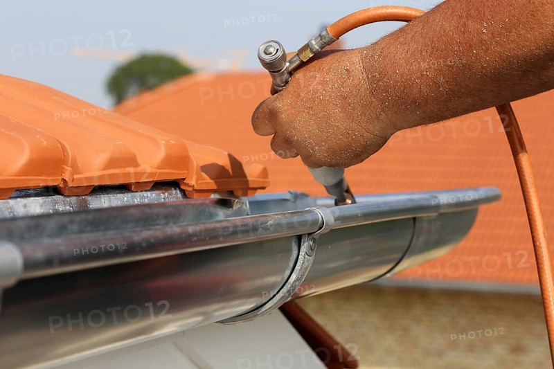 Roofer doing tinsmith work on a gutter