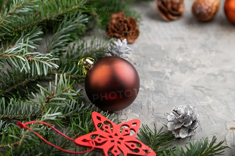 Christmas or New Year composition. Decorations, cones, cinnamon, fir and spruce branches, cup of coffee, wool scarf on a gray concrete background. Side view, copy space