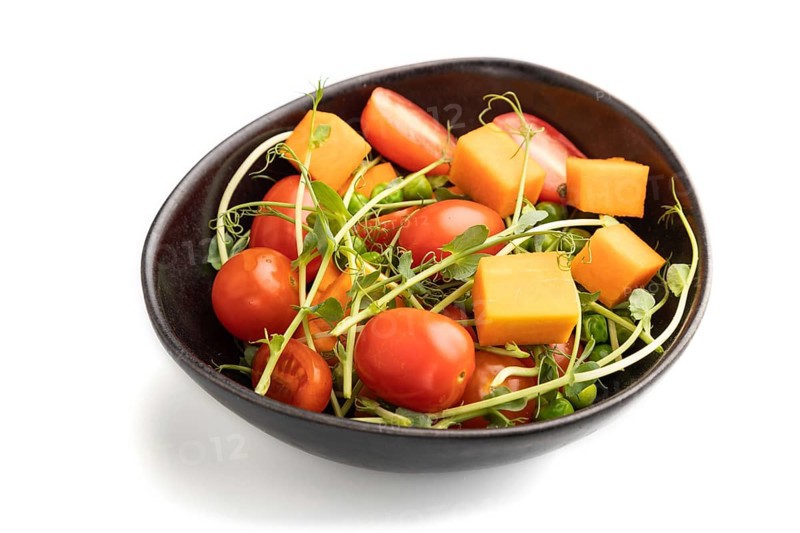 Vegetarian vegetable salad of tomatoes, pumpkin, microgreen pea sprouts isolated on white background. Side view, close up