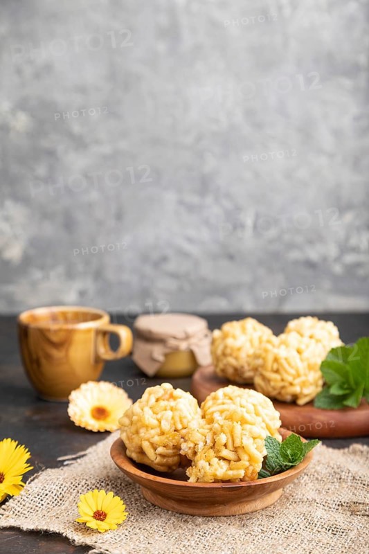 Traditional Tatar candy chak-chak made of dough and honey with cup of coffee on a black concrete background and linen textile. Side view, close up, selective focus, copy space