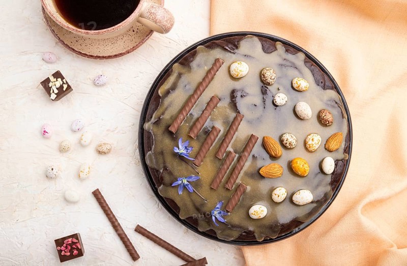 Homemade chocolate brownie cake with caramel cream and almonds with cup of coffee on a white concrete background and orange textile. top view. flat lay, close up