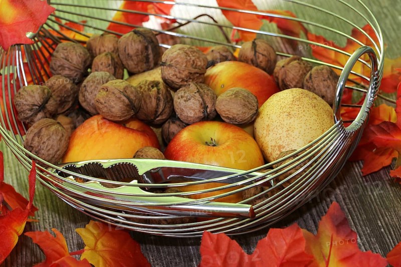 Apples, pears and walnuts on a rustic wooden table as an autumnal motif