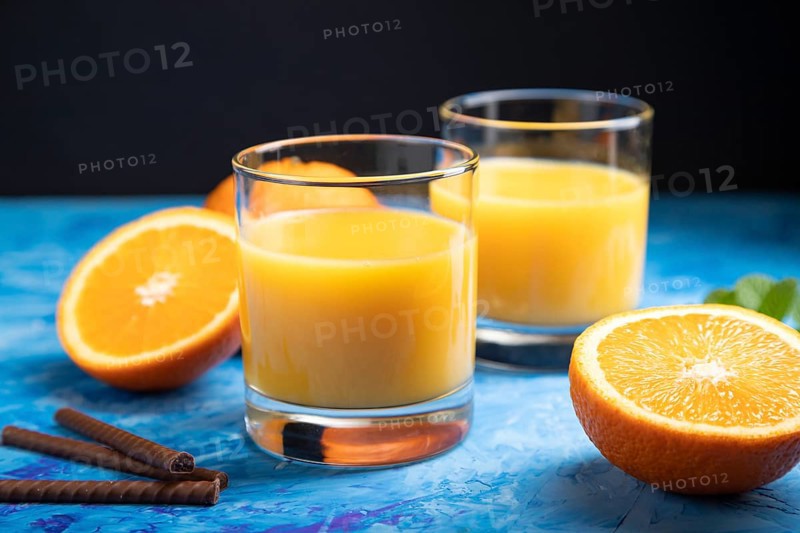 Glass of orange juice on a black and blue background. Hard light, contrast. Side view, close up