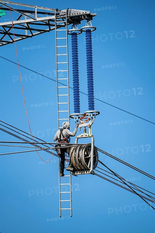 Construction of a new line route, 380 KV extra-high voltage line between Osterath and Gohr, near Neuss, fitter on ladder at great height, tensioning the lines, North Rhine-Westphalia, Germany, Europe