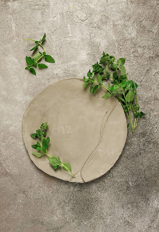 Grey clay plate, handmade, with basil branches, top view, food background, food wallpaper for menu