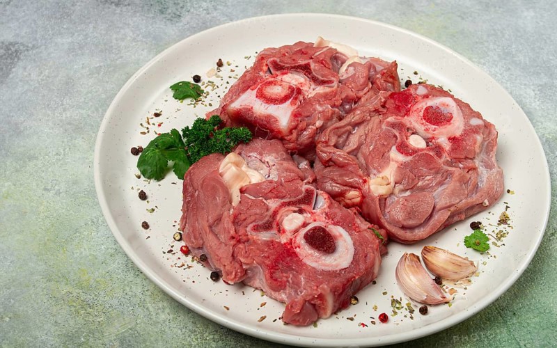 Raw steak, calf's neck on the bone, fresh meat, on a white plate, top view, no people