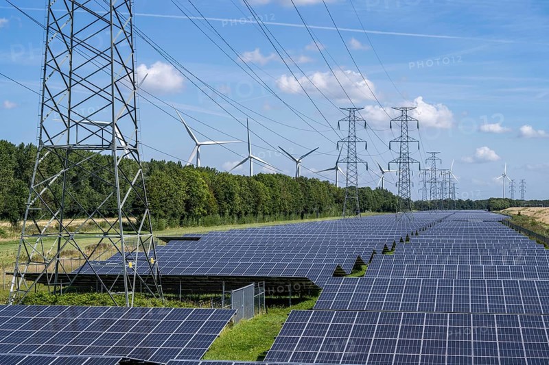 High-voltage power line route, the space underneath is used for a solar park over 5 km long, behind it a wind farm, in the harbour area of Vlissingen-Oost, Netherlands