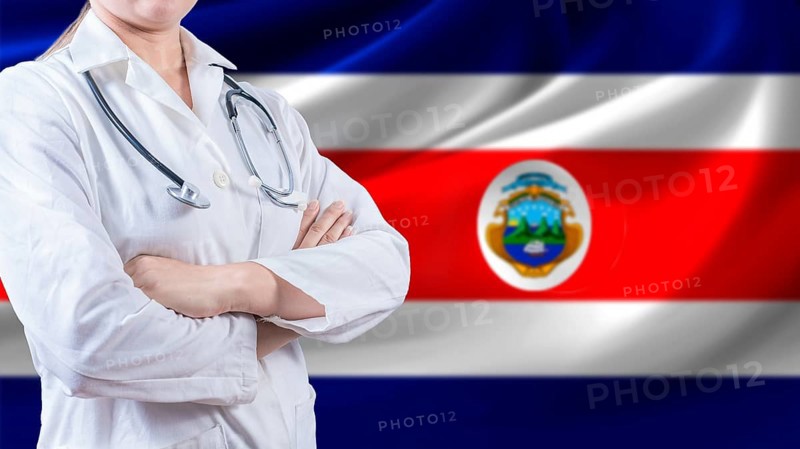 Female doctor with crossed arms with Costa Rican flag in the background. Health care concept with Costa Rica flag in background