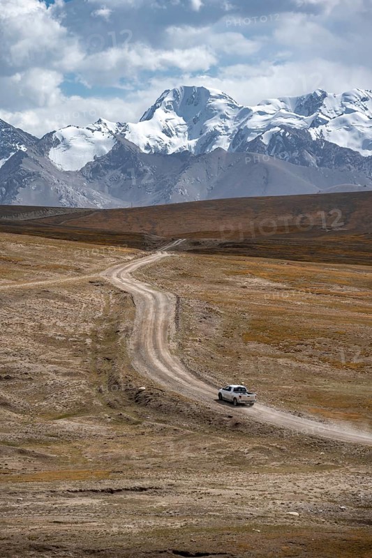 Off-road vehicle on a gravel track, glaciated and snow-covered peaks, Ak Shyrak Mountains, near Kumtor, Kara-Say, Tian Shan, Kyrgyzstan, Asia