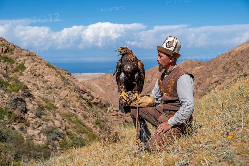 Traditional Kyrgyz eagle hunter with eagle in the mountains, near Kysyl-Suu, Kyrgyzstan, Asia