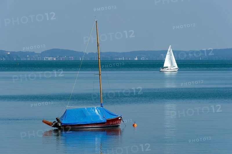Covered and sailing boat underway on calm waters, Bernried am Starnberger See, Upper Bavaria, Bavaria, Germany, Europe