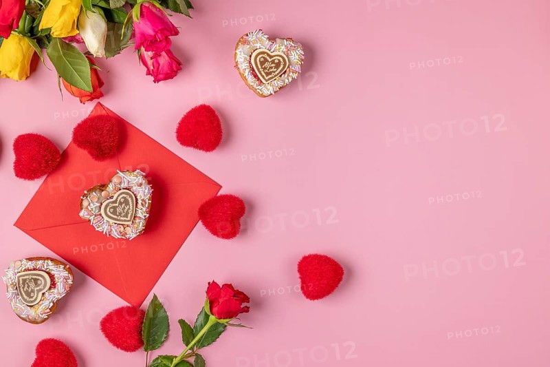 Valentine's Day composition with roses, hearts and envelope, heart-shaped cupcakes, on a pink background