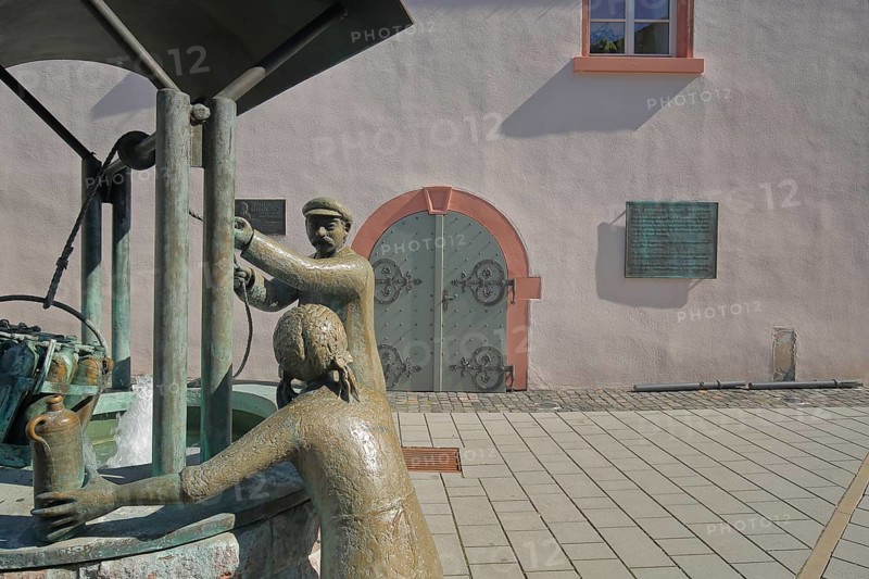 Drawing fountain from 1999 with sculptures and monument to mineral water town history, historical, bronze, male figure, pulling, pulling up, transporting, rope, basket, crate with water bottles, bottles, Old Town Hall, Market Square, Bad Vilbel, Wetterau, Hesse, Germany, Europe