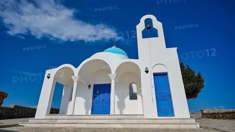 White church with blue doors and a bell in front of a blue sky and tree, Church of Profitis Ilias, above Nikia, Nikia, Nisyros, Dodecanese, Greek Islands, Greece, Europe