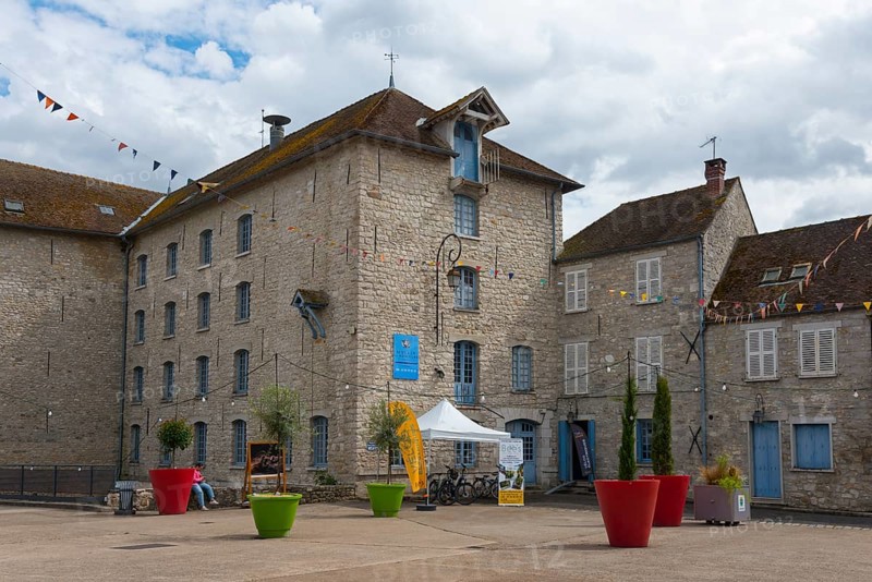 Historische Steinhäuser und bunte Blumentöpfe auf einem Platz mit Wimpeln, La Minoterie, Le Moulin de Nemours, Getreidemühle, Nemours, Département Seine-et-Marne, Region Île-de-France, Ile-de-France, Frankreich