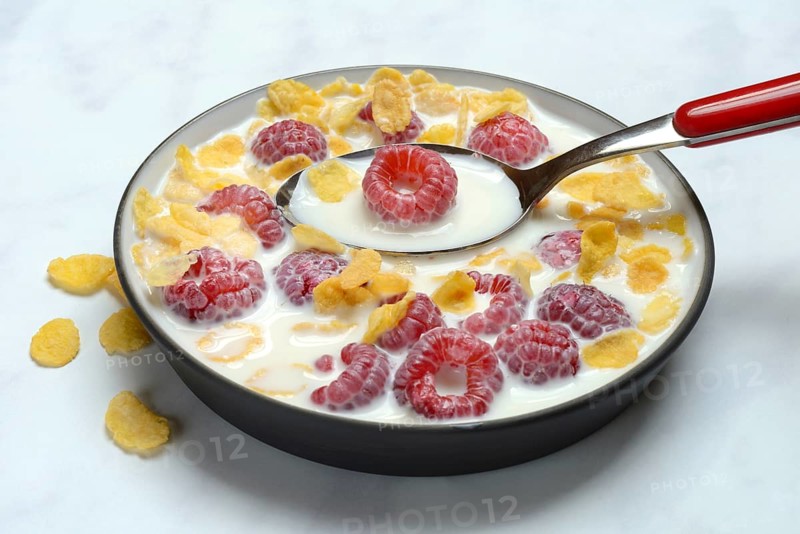 Raspberries and cornflakes with milk in a bowl, Rubus idaeus