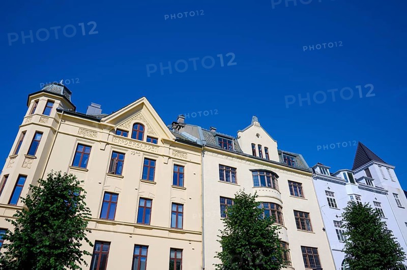 Historic Jugendstiel façade with large windows and trees in front under a clear blue sky, Bryggen, Bergen, Vestland, Norway, Europe