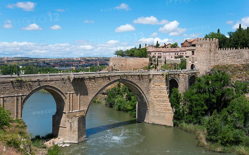 Historic stone bridge over river in rural setting with neighbouring old buildings, Puente de San Martín, Saint Martin's Bridge, Toledo, Tagus River, Castilla-La Mancha, Spain, Europe