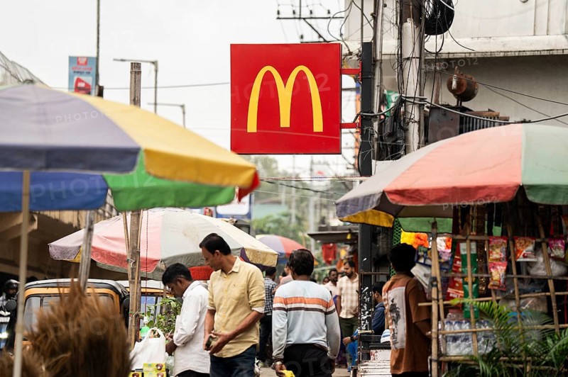 People walks by a McDonald's sign on October 26, 2024 in Guwahati, India. McDonald's recent food safety issues causing a 5% stock drop, after e-coli contamination in the United States