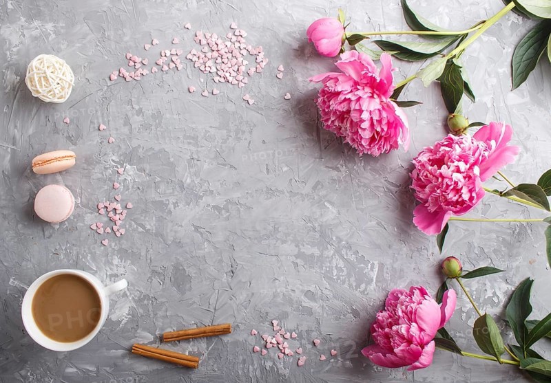 Pink peony flowers and a cup of coffee on a gray concrete background. Morninig, spring, fashion composition. Flat lay, top view, copy space