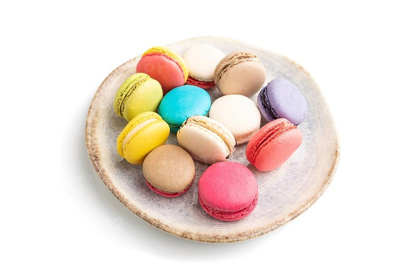 Multicolored macaroons on ceramic plate isolated on white background. side view, still life, close up. Breakfast, morning, concept