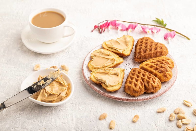 Homemade waffle with peanut butter and cup of coffee on a gray concrete background. side view, close up