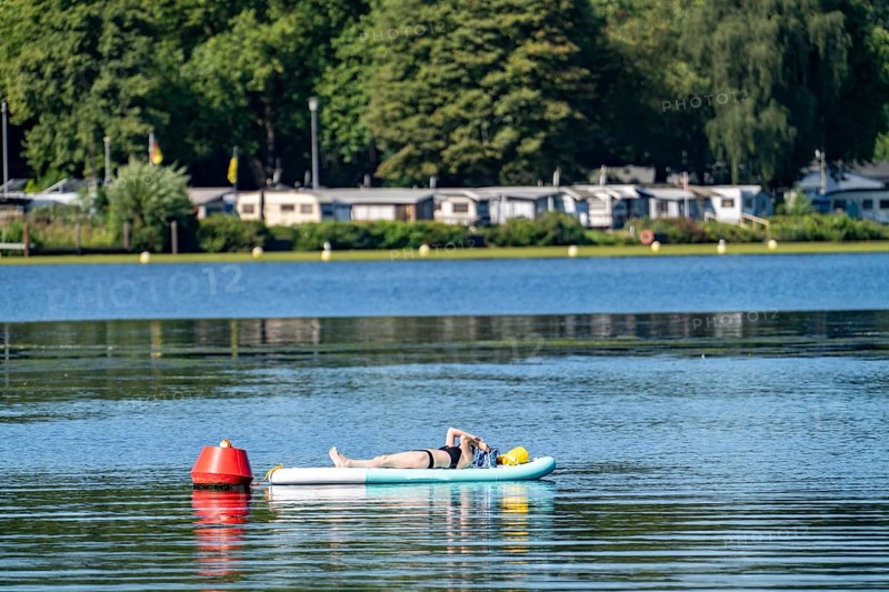 Lake Baldeney, Ruhrstausee, SUP as a reading island, young woman enjoying the summer, on her stand-up paddle board, moored to a buoy, Essen, North Rhine-Westphalia, Germany, Europe