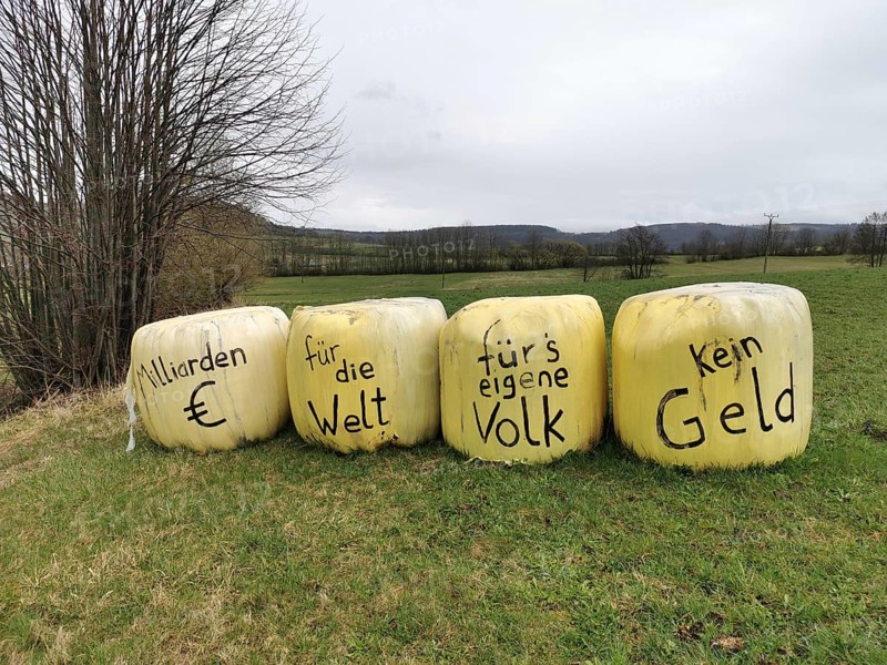 Billions of euros for the world, no money for our own people, farmers protest on bales of grass wrapped in foil against the waste of taxpayers' money by the German government