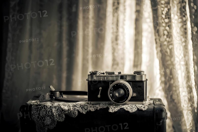 Vintage film camera surrounded by black and white photos in soft sunlight, AI generated