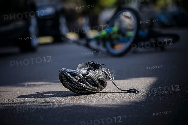 Symbol photo on the subject of bicycle accidents (posed scene) . A broken bicycle helmet lies next to a bicycle on a road Berlin, 21/08/2024