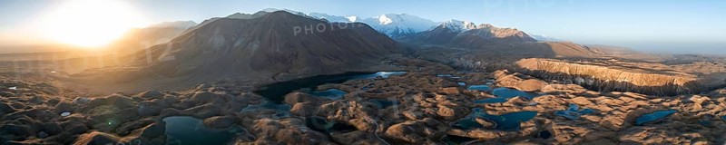 Panorama, White glaciated and snow-covered mountain peak Pik Lenin at sunrise, hilly landscape with golden meadows and lakes, aerial view, Trans Alay Mountains, Pamir Mountains, Osh Province, Kyrgyzstan, Asia