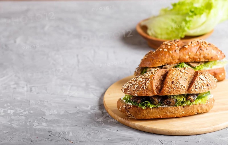 Sprats sandwiches with lettuce and cream cheese on wooden board on a gray concrete background. side view, copy space, selective focus