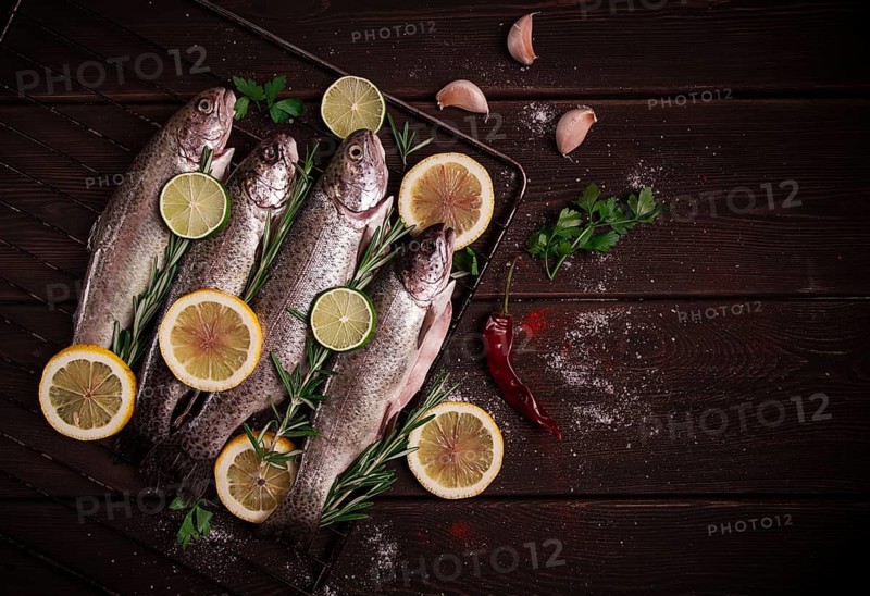 Raw rainbow trout, with lemon and herbs, on a wooden table, no people