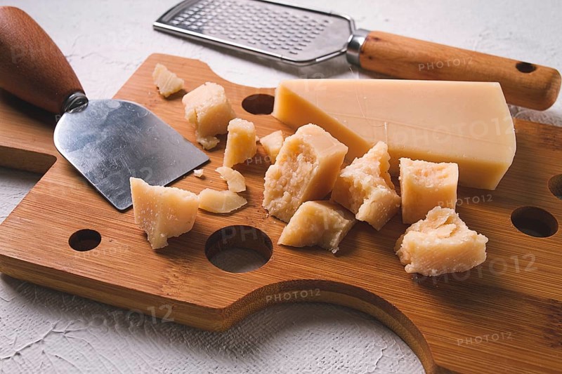Hard cheese, parmesan, on a cutting board, cheese knife, grater, top view, no people