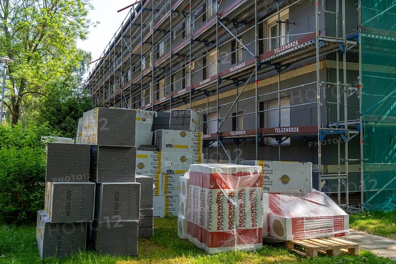 Energetic renovation of an apartment building, thermal insulation, building materials, insulation materials stored in front of the construction site, scaffolded building