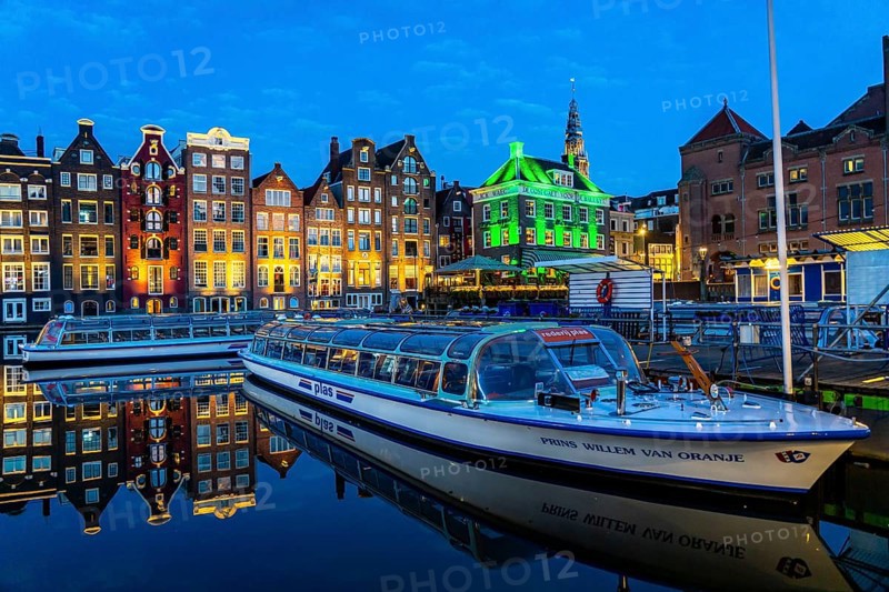 Canal houses on the Damrak, in the centre of the old town of Amsterdam, harbour, starting point of many canal tours, in the evening, church tower of the Oude Kerk, Netherlands