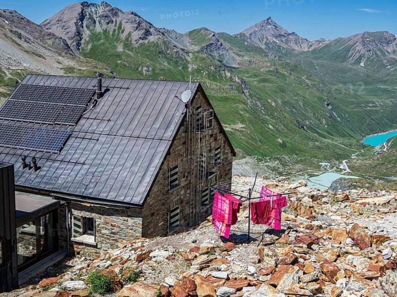 Colored bed linen dries in the sun, mountain hut Cabane de Moiry, lake Lac de Moiry in the back, Valais, Switzerland, Europe