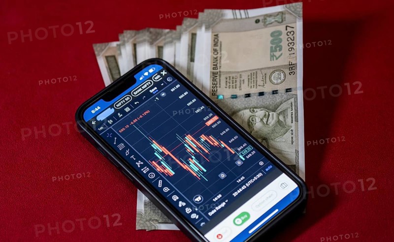 Stock market graph or chart display on a mobile phone against Indian 500 rupee paper currency note