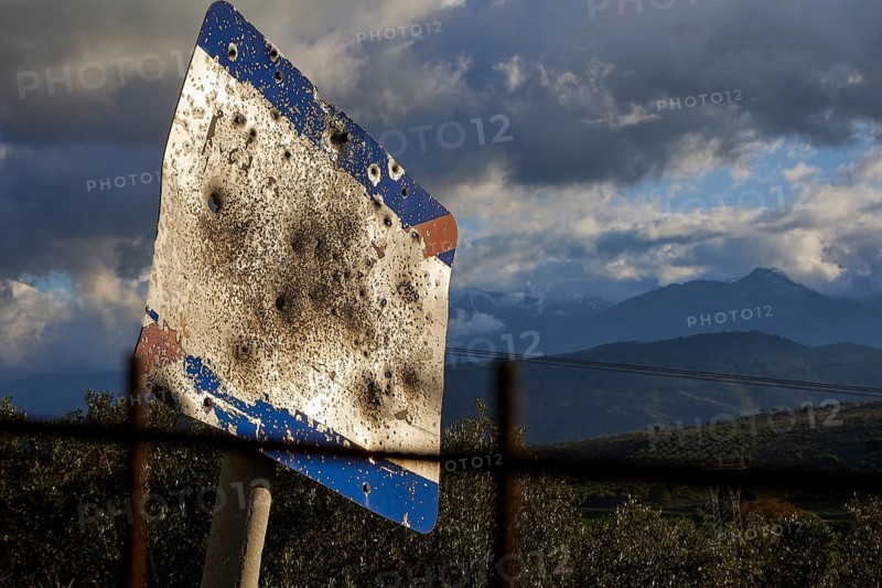 A rusty, tattered road sign in front of a mountainous landscape under a cloudy sky, Lefka Ori, White Mountains, mountain massif, west, Crete, Greece, Europe