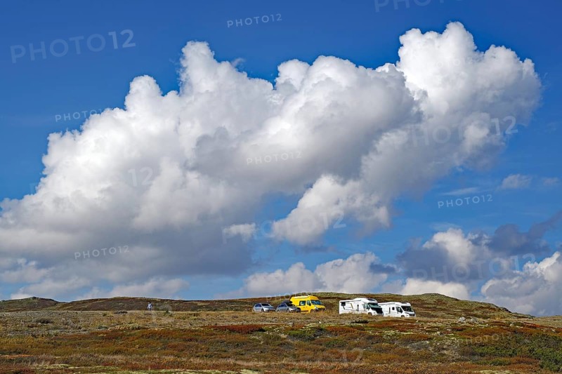 Motorhomes on a hilly landscape under large, dramatic cloud formations in the blue sky, autumn, Snöhetta, Hjerkinn, Dovrefjell-Sunndalsfjella National Park, Norway, Europe