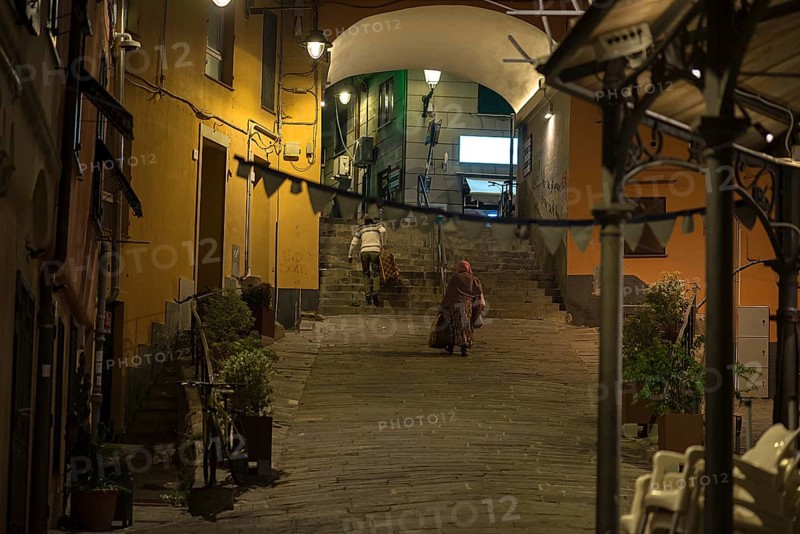 Two residents with suitcases, returning home in the evening from a trip, old town of Genoa, Italy, Europe