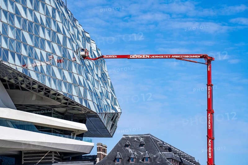 The Antwerp Port Authority building, Havenhuis, former fire brigade barracks in the harbour, renovated and with an attached glass structure, in the shape of a ship's hull, administrative headquarters of the Antwerp Port Authority, designed by Zaha Hadid, building cleaners clean the windows, truck work platform of the German rental company Gerken, Antwerp, Flanders, Belgium, Europe