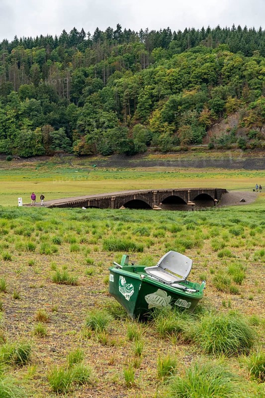The Edersee, near Waldeck, the third largest reservoir in Germany, currently has only just under 13% of its normal level, the lake was last full in May 2022, dried out due to lack of rain, Asel bridge, exposed by the low water, stranded fishing boat, otherwise flooded, the lake shore and the lake bottom is overgrown with fresh grass, Hesse, Germany, Europe