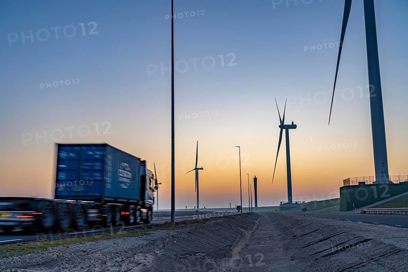 Lorry on the road from Euromax Terminal Rotterdam, ENECO wind farm on the dike around the port of Maasvlakte 2, 22 wind turbines with a capacity of 116 megawatts, sunset, Rotterdam, Netherlands