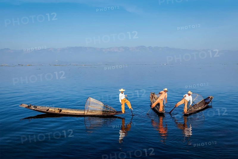Myanmar travel attraction landmark, Traditional Burmese fishermen with fishing nets on boats at Inle lake in Myanmar famous for their distinctive one legged rowing style