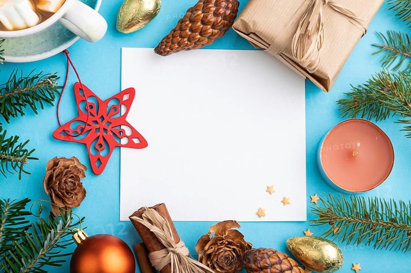 Christmas or New Year composition, template. Decorations, box, cinnamon, cones, fir and spruce branches, cup of coffee, on a blue paper background. Top view, copy space, flat lay