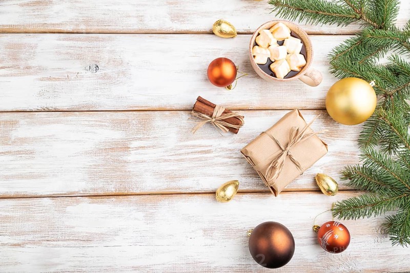 Christmas or New Year composition. Decorations, box, golden balls, cinnamon, fir and spruce branches, cup of coffee, on a white wooden background. Top view, copy space, flat lay