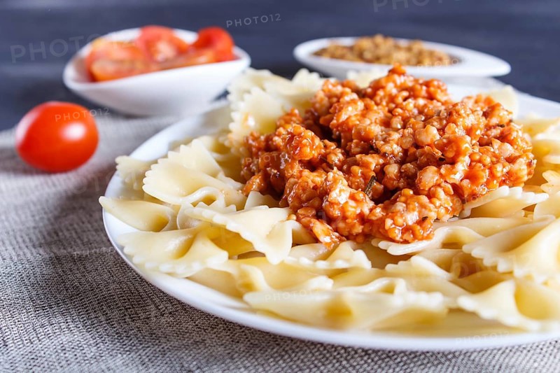 Farfalle bolognese pasta with minced meat on black wooden background. close up, selective focus