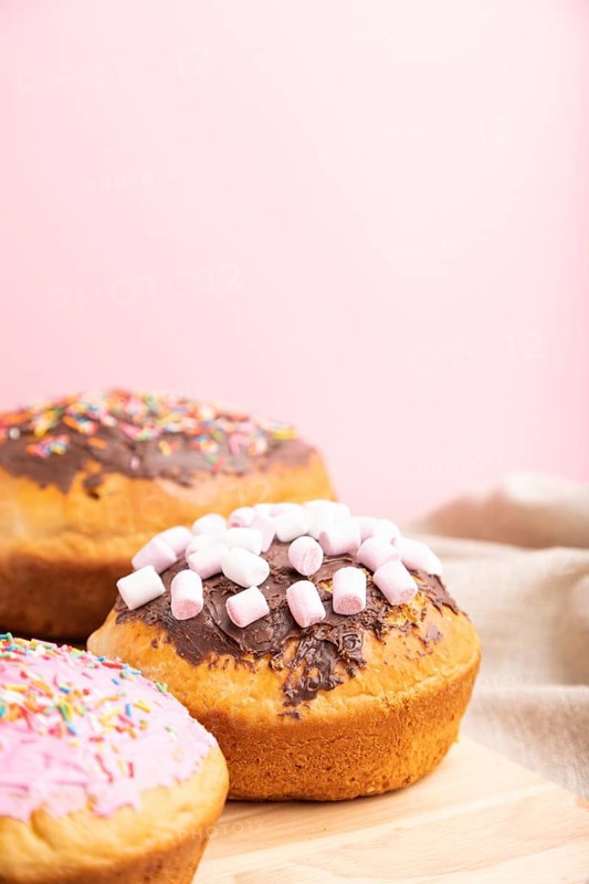 Homemade glazed and decorated easter pies with chocolate eggs and rabbits on a gray and pink background and linen textile. Side view, selective focus, copy space