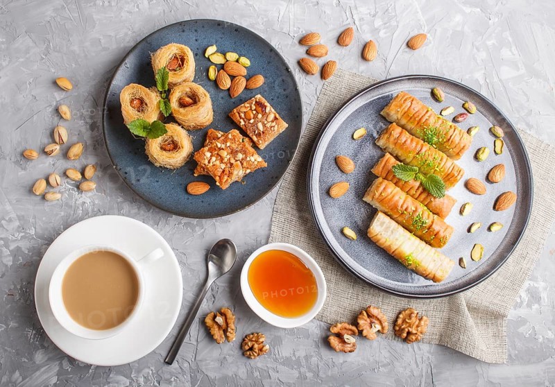 Set of various traditional arabic sweets: baklava, kunafa, basbus in ceramic plates on a gray concrete background. top view, flat lay